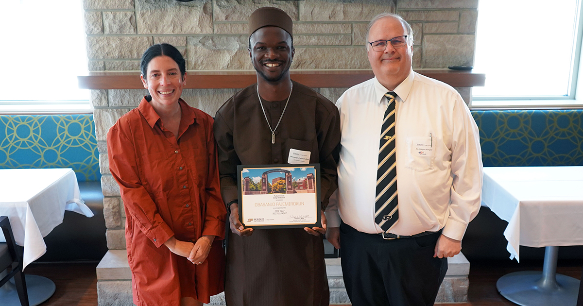 Obasanjo Fajemirokun holding a certificate. He is surrounded by Stephanie Scherer and Wayne Wright.