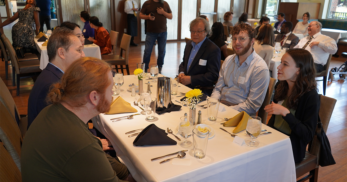 A group of professors and graduate students seated at a dinner table.