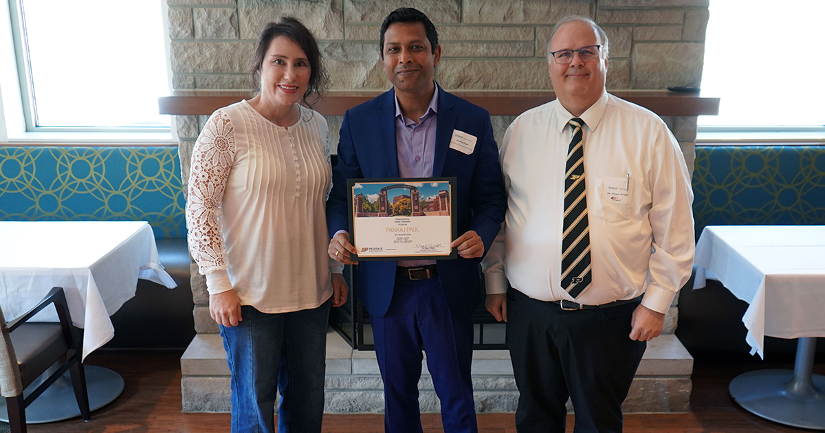 Pankaj Paul holding a certificate. He is surrounded by Victoria Lowell and Wayne Wright.